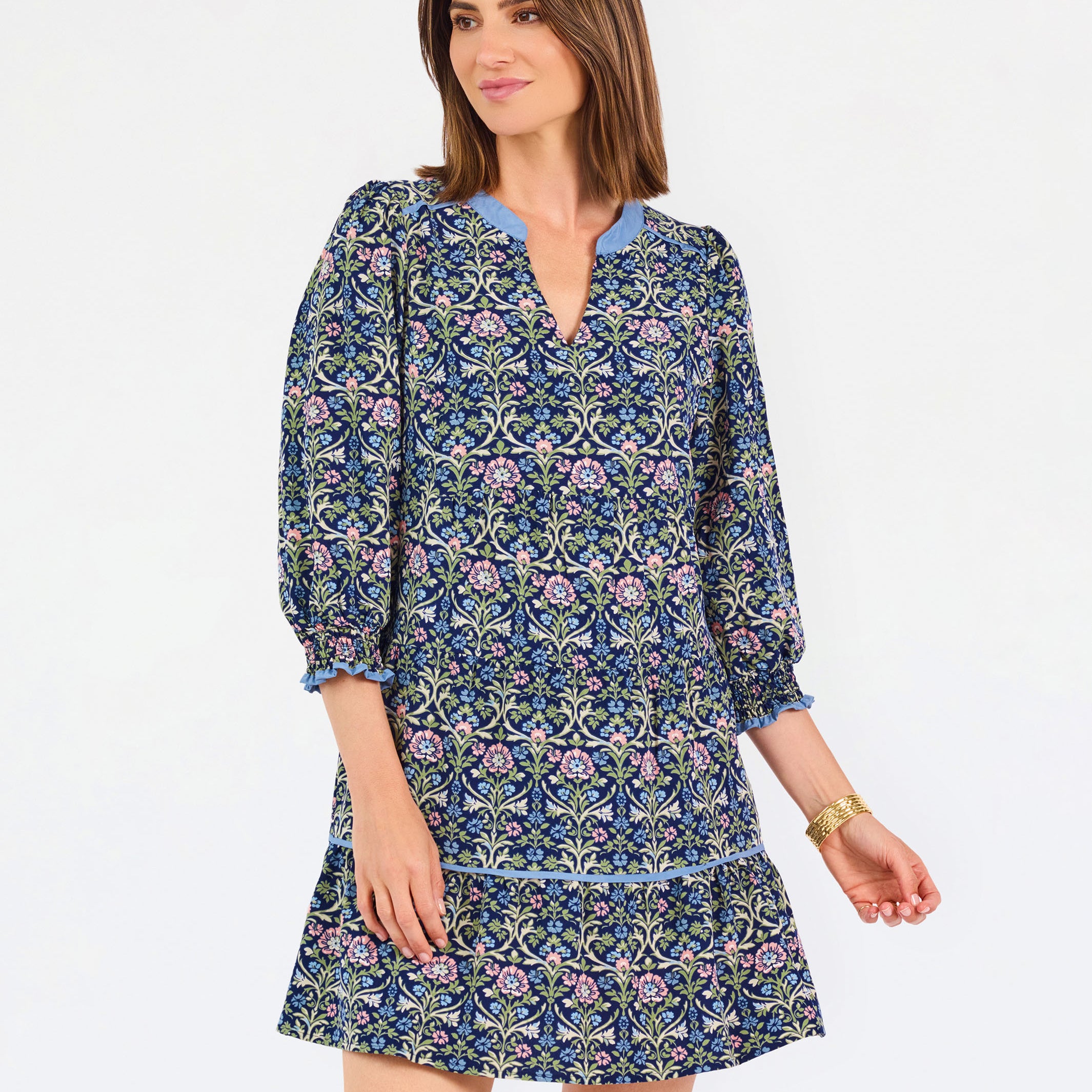 Women with short brown hair wearing a blue printed mini dress with three quarter puff sleeves and blue trim 