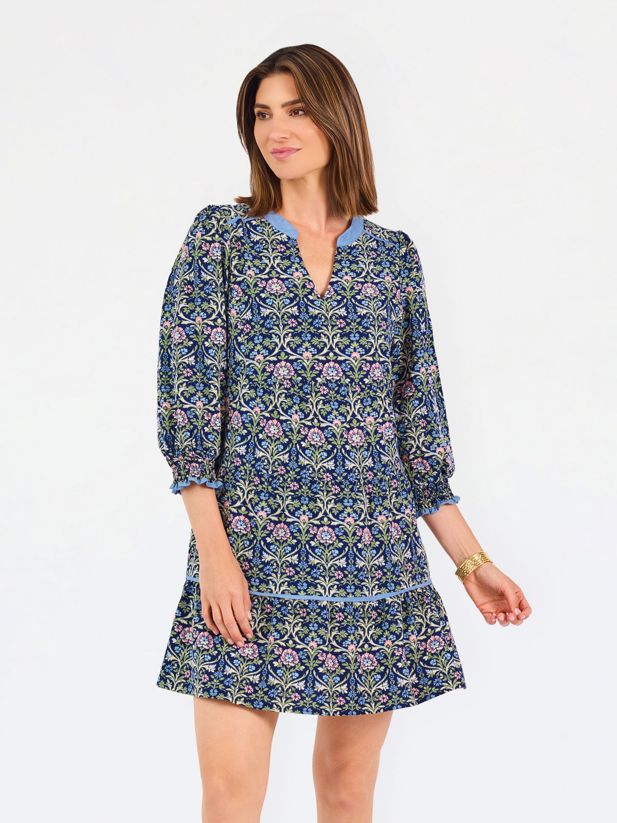 Women with short brown hair wearing a blue printed mini dress with three quarter puff sleeves and blue trim 