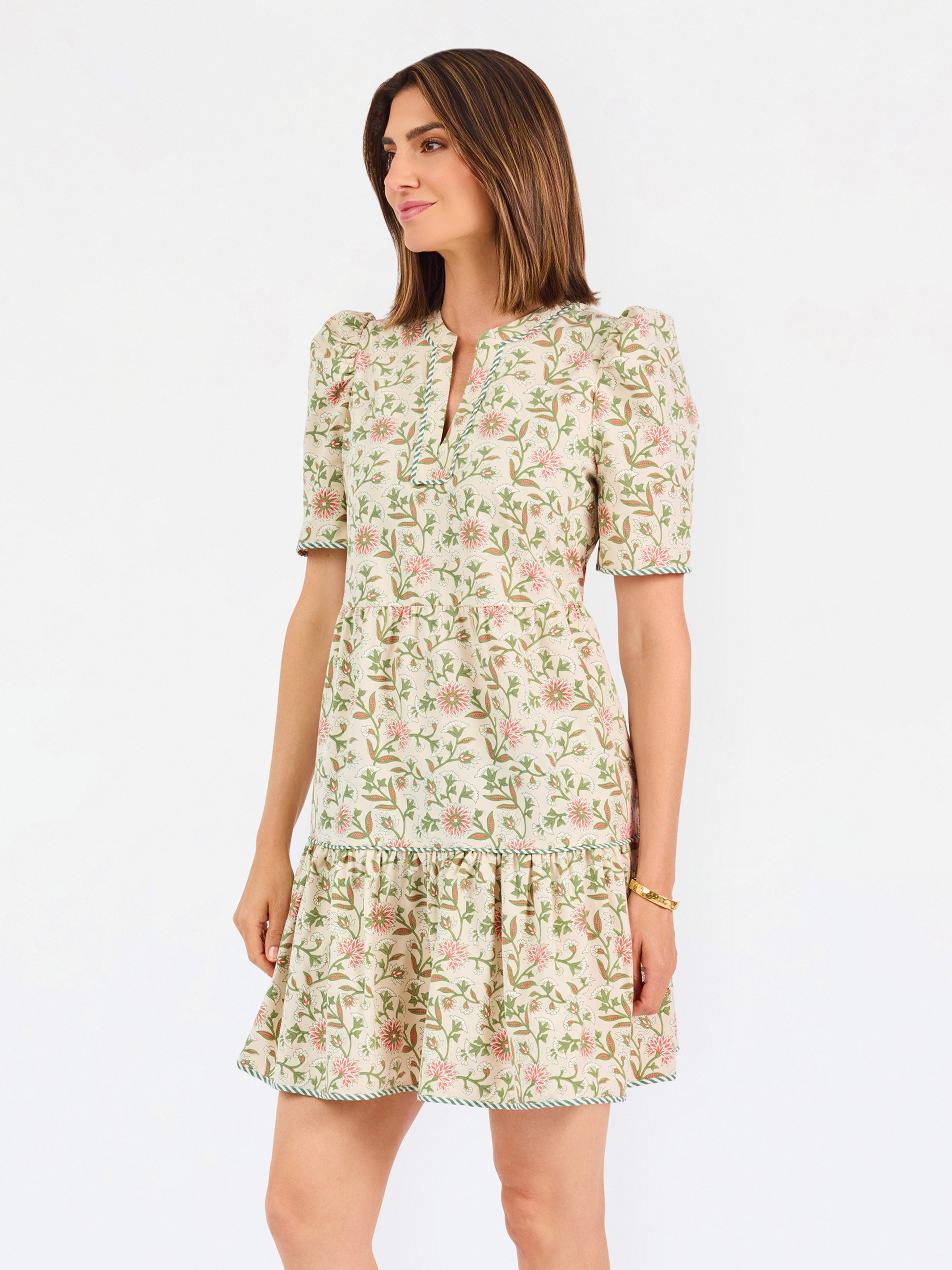 Women with short brown hair wearing a floral green and tan mini dress with puff sleeves and green stripe trim