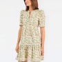 Women with short brown hair wearing a floral green and tan mini dress with puff sleeves and green stripe trim