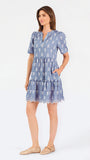 A woman wearing a dusty blue short-sleeve dress with a white floral print, featuring a split neckline and puff sleeves, shown against a plain white background.