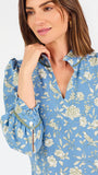 A woman modeling a light blue long-sleeve mini dress with a cream floral print, standing against a plain white studio background.
