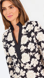 Woman wearing a three quarter sleeve dress with black and tan flowers on a white background. 