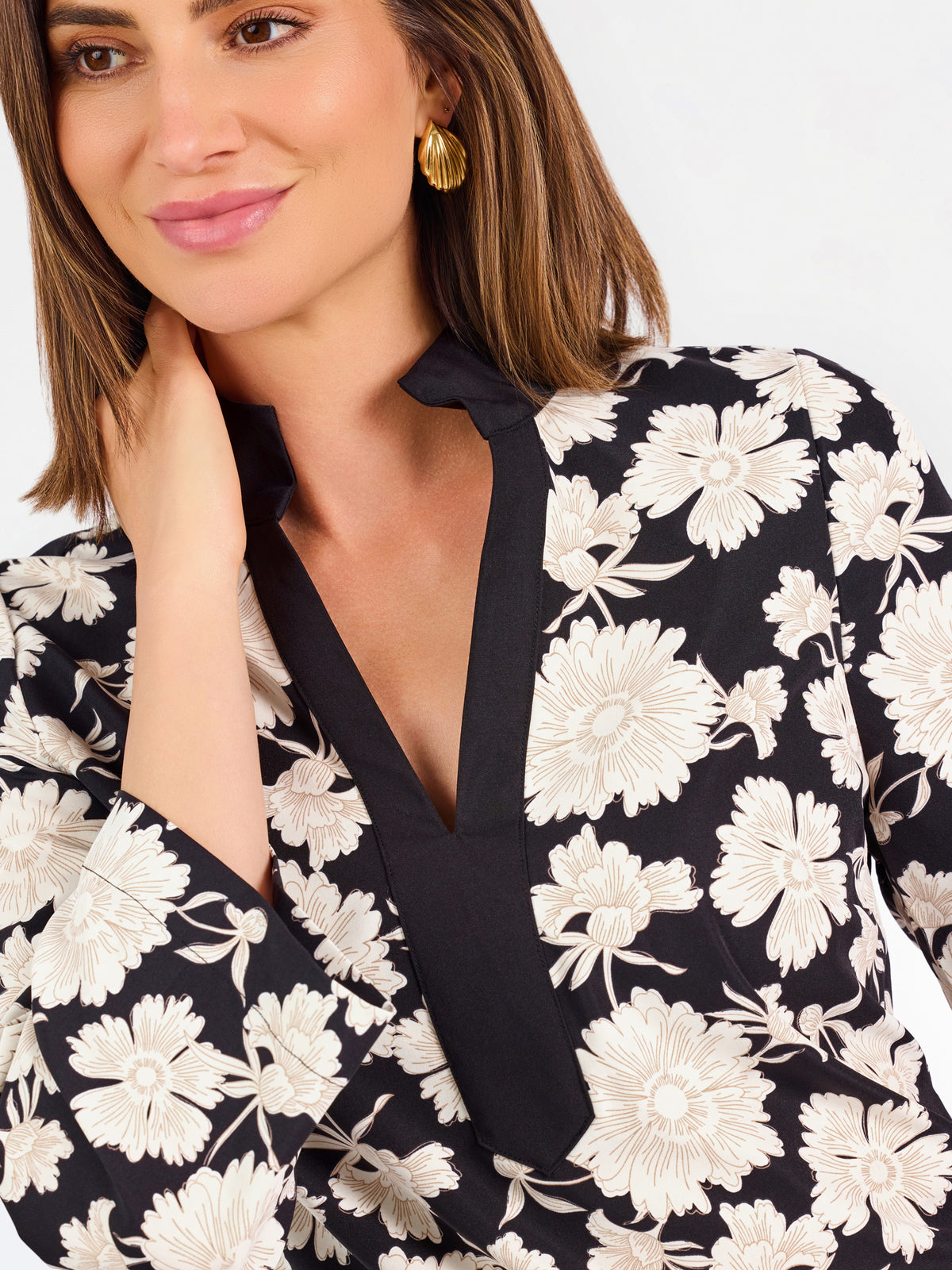 Woman wearing a three quarter sleeve dress with black and tan flowers on a white background. 