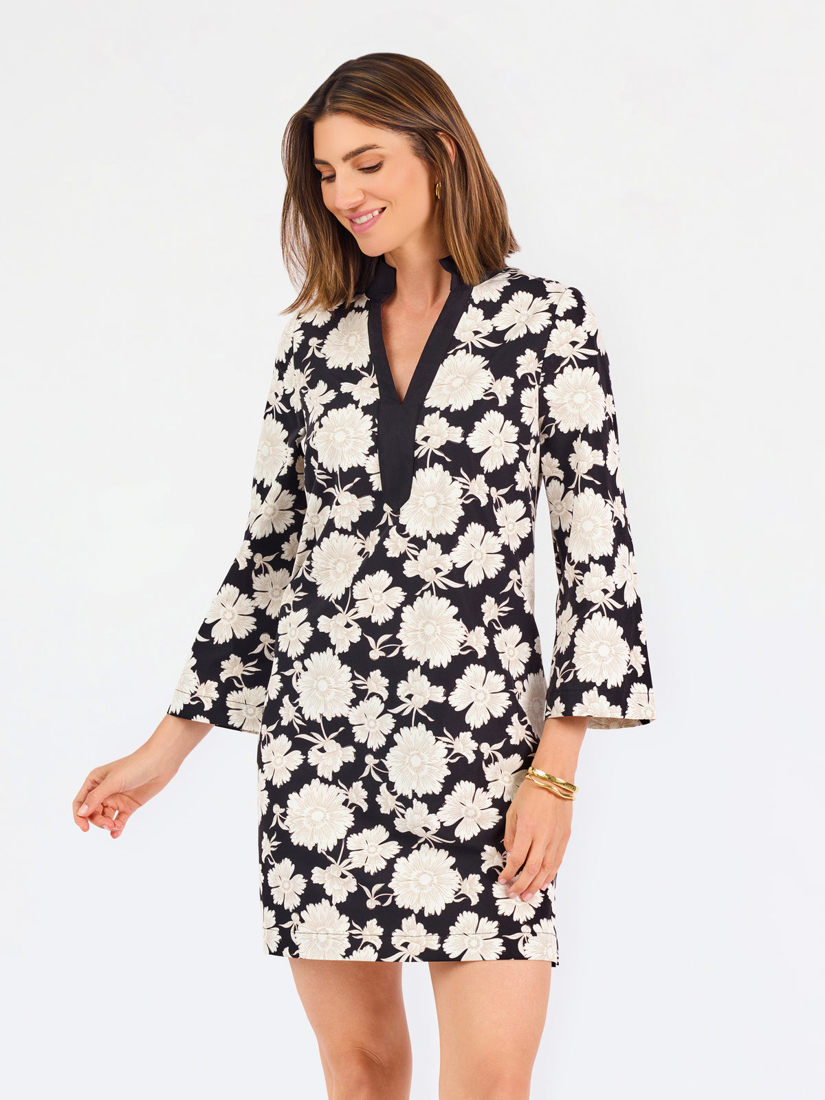 Woman wearing a three quarter sleeve dress with black and tan flowers on a white background. 