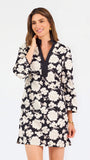 Woman wearing a three quarter sleeve dress with black and tan flowers on a white background. 