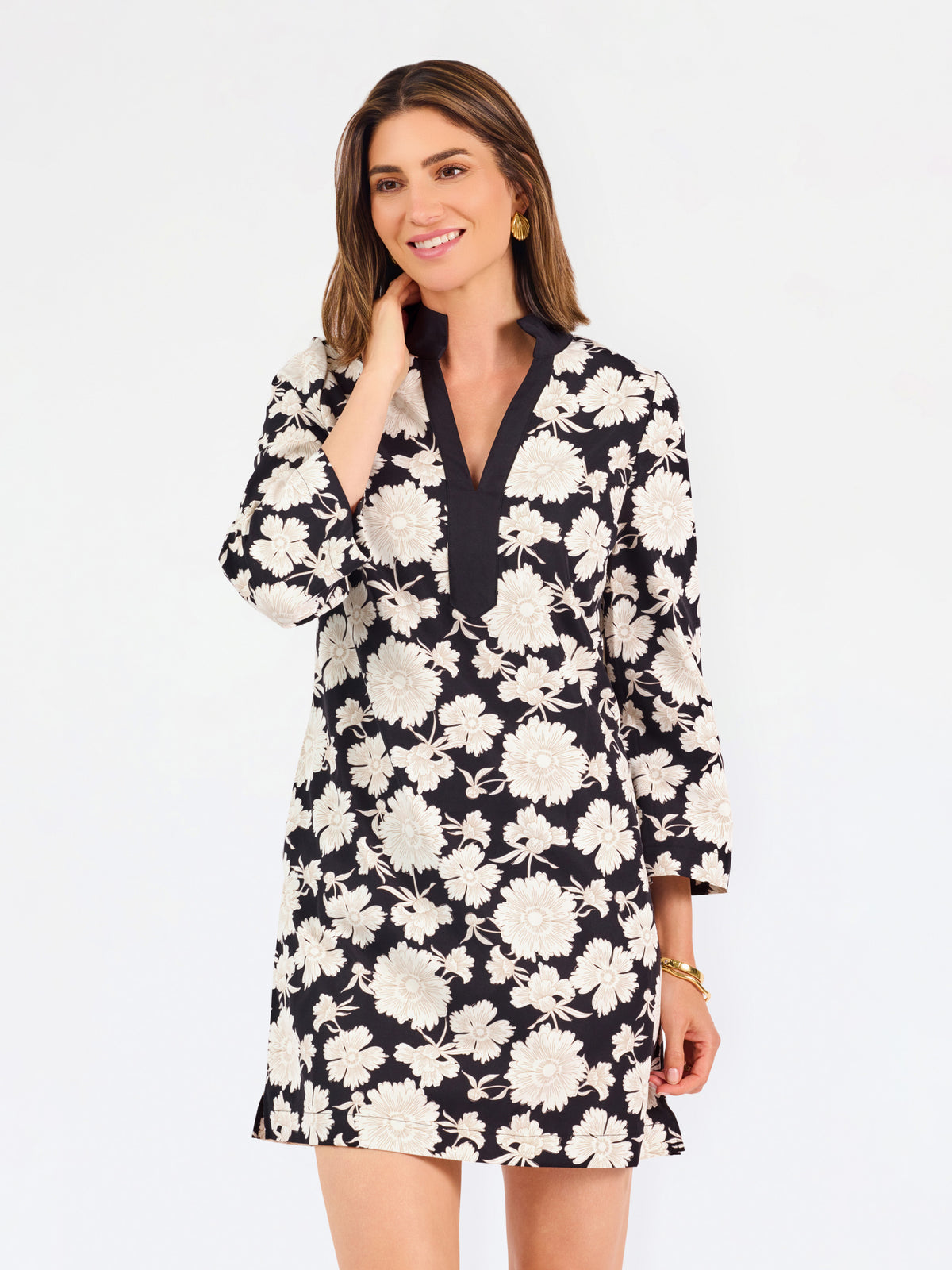 Woman wearing a three quarter sleeve dress with black and tan flowers on a white background. 