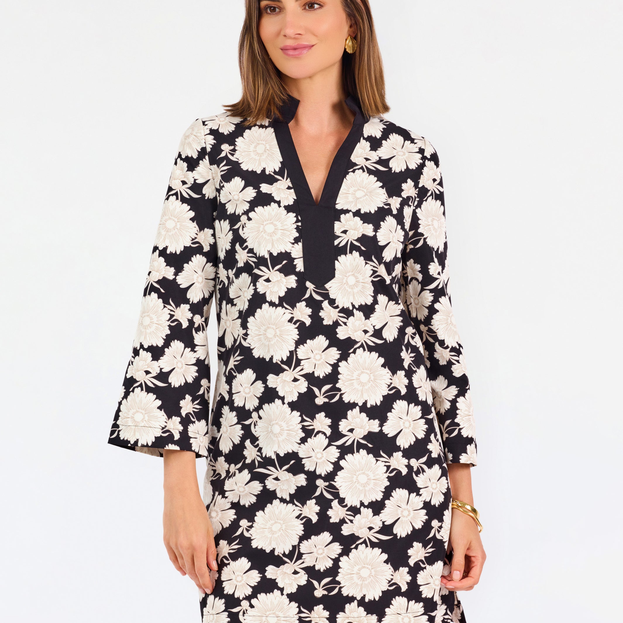 Woman wearing a three quarter sleeve dress with black and tan flowers on a white background. 