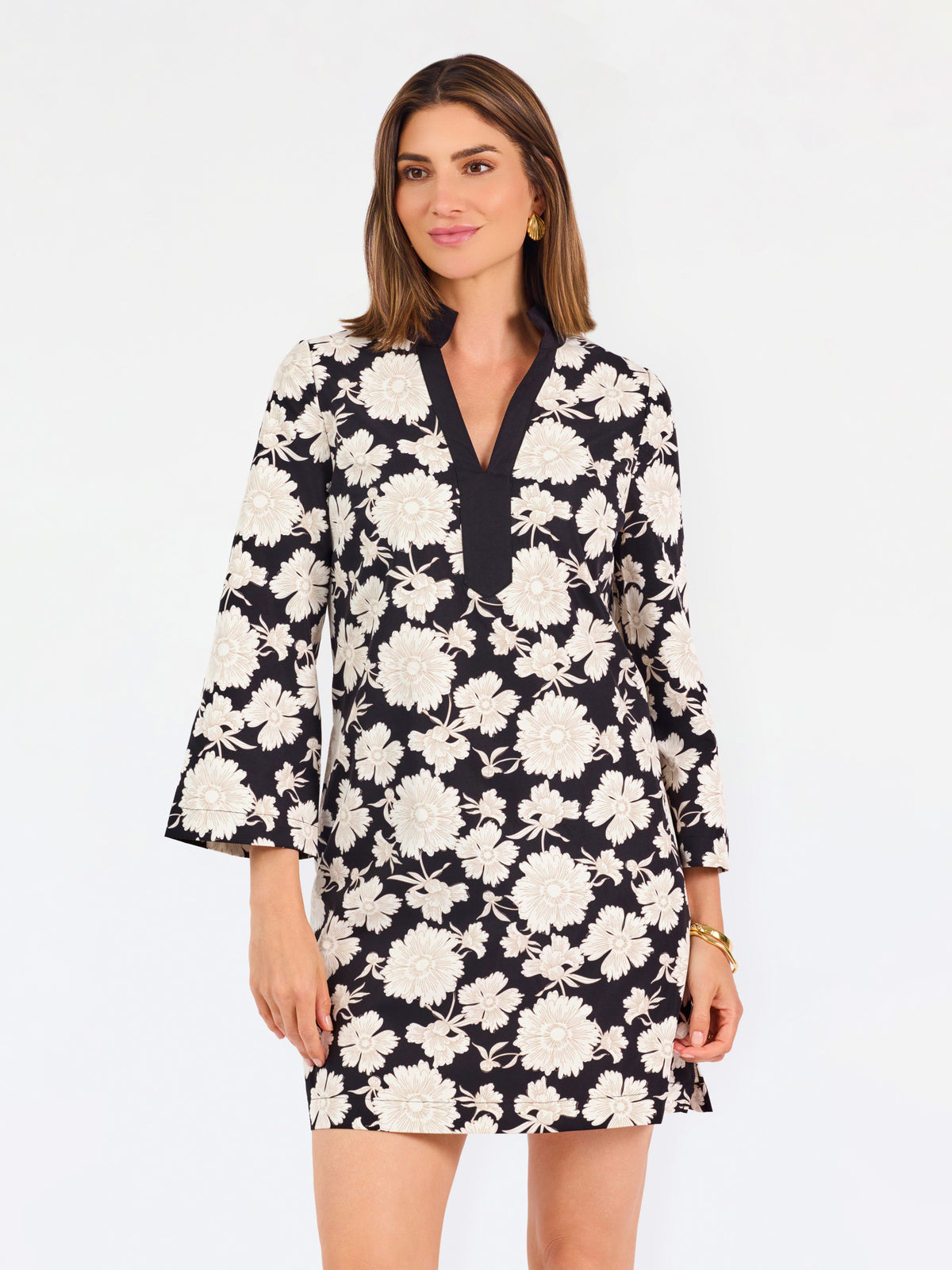 Woman wearing a three quarter sleeve dress with black and tan flowers on a white background. 