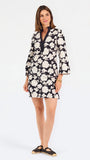 Woman wearing a three quarter sleeve dress with black and tan flowers on a white background. 