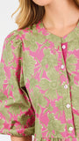 A woman modeling a midi dress with a green and pink floral pattern, short puff sleeves, and a gathered waist, set against a plain white studio background.