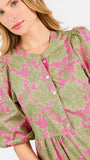 A woman modeling a midi dress with a green and pink floral pattern, short puff sleeves, and a gathered waist, set against a plain white studio background.