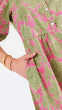 A woman modeling a midi dress with a green and pink floral pattern, short puff sleeves, and a gathered waist, set against a plain white studio background.