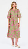 A woman modeling a midi dress with a green and pink floral pattern, short puff sleeves, and a gathered waist, set against a plain white studio background.