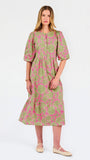 A woman modeling a midi dress with a green and pink floral pattern, short puff sleeves, and a gathered waist, set against a plain white studio background.