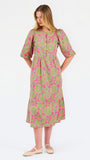 A woman modeling a midi dress with a green and pink floral pattern, short puff sleeves, and a gathered waist, set against a plain white studio background.