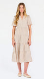 A woman modeling a short-sleeve midi dress with vertical beige and white stripes, featuring a tiered ruffle hem and a split neckline, set against a plain white studio background.