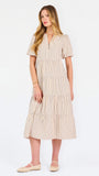 A woman modeling a short-sleeve midi dress with vertical beige and white stripes, featuring a tiered ruffle hem and a split neckline, set against a plain white studio background.