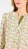 Woman wearing a tan floral blouse and jeans on a white background