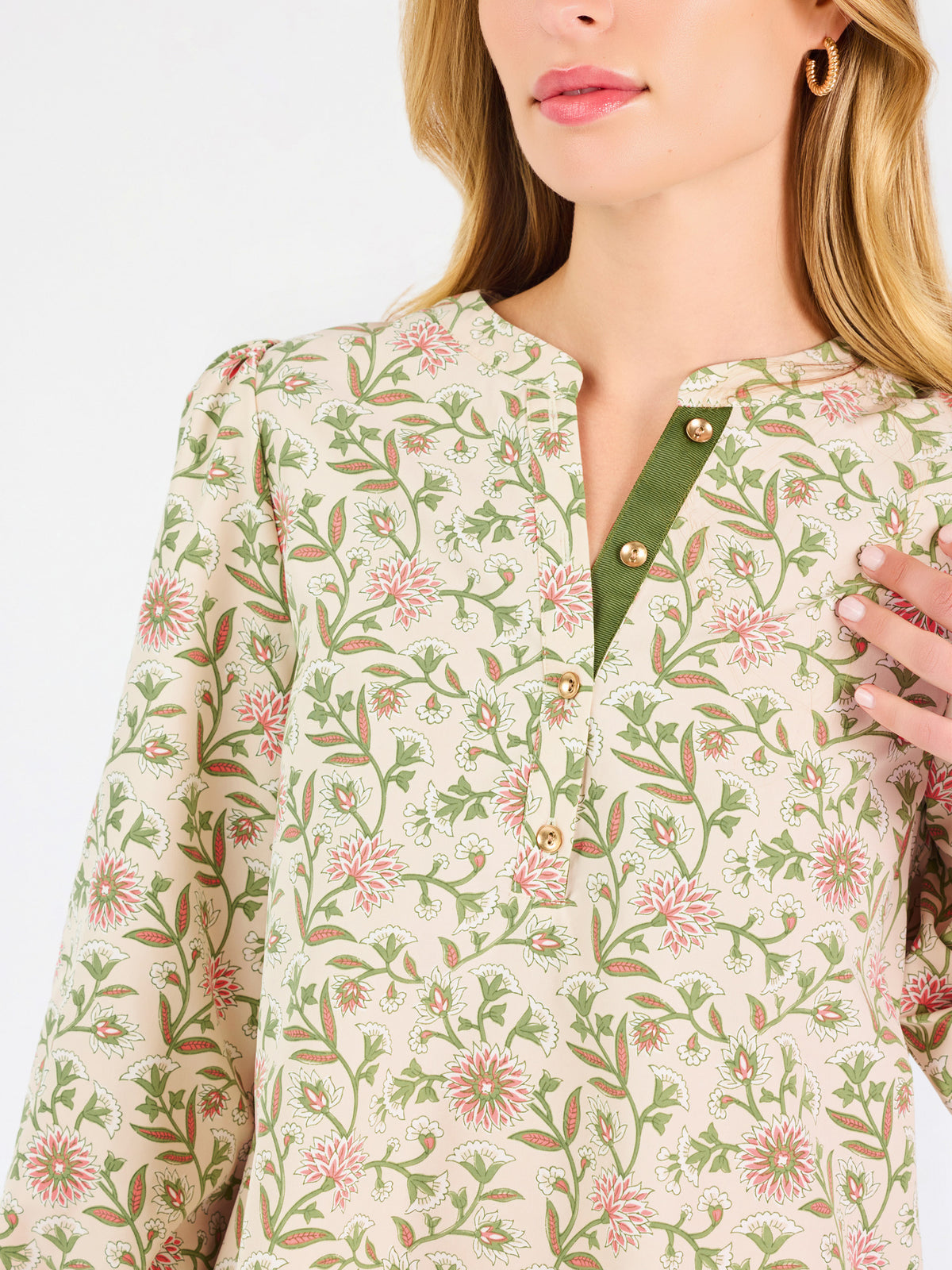 Woman wearing a tan floral blouse and jeans on a white background