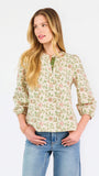 Woman wearing a tan floral blouse and jeans on a white background