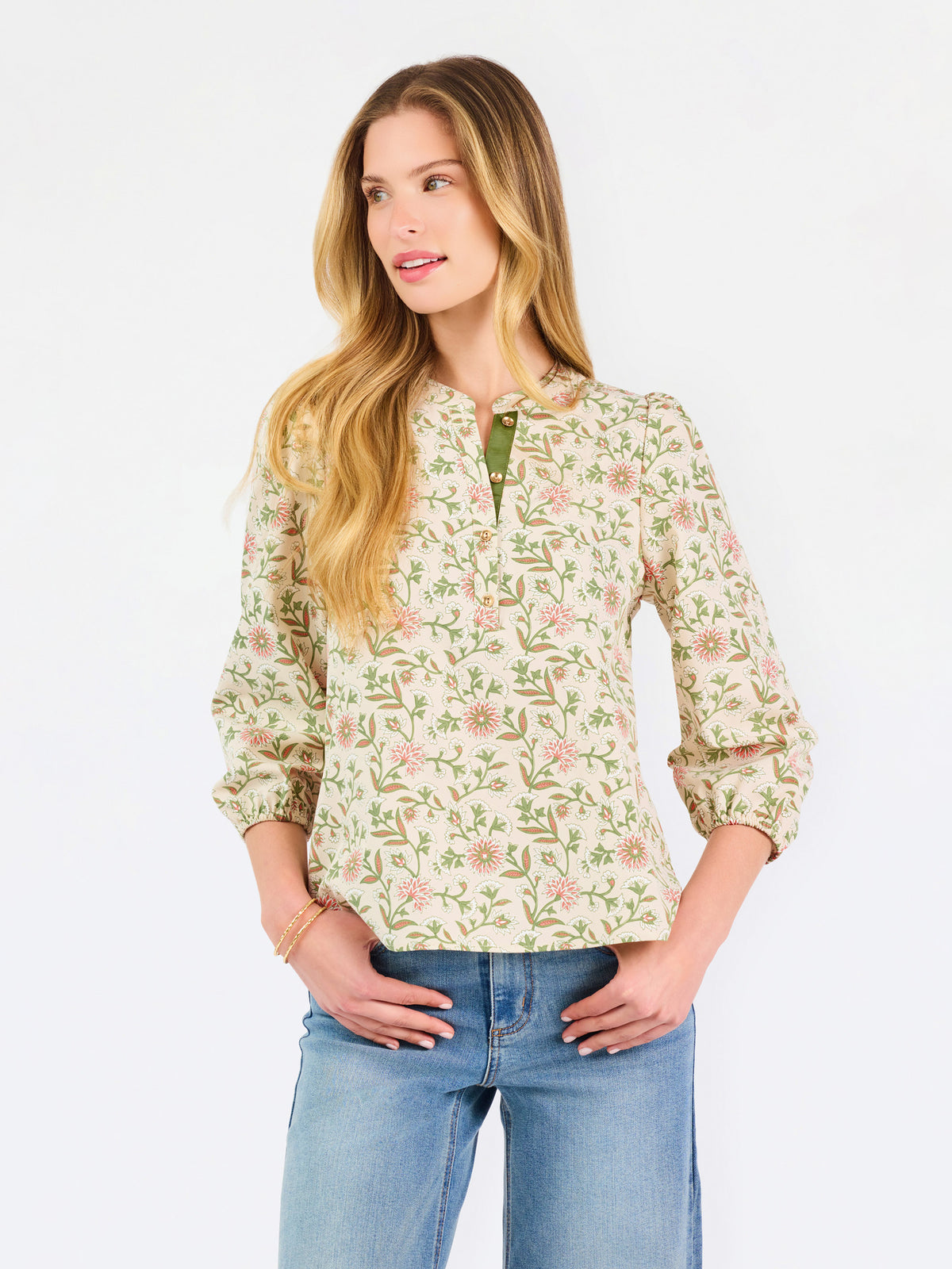 Woman wearing a tan floral blouse and jeans on a white background