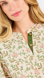Woman wearing a tan floral blouse and jeans on a white background