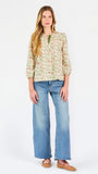 Woman wearing a tan floral blouse and jeans on a white background