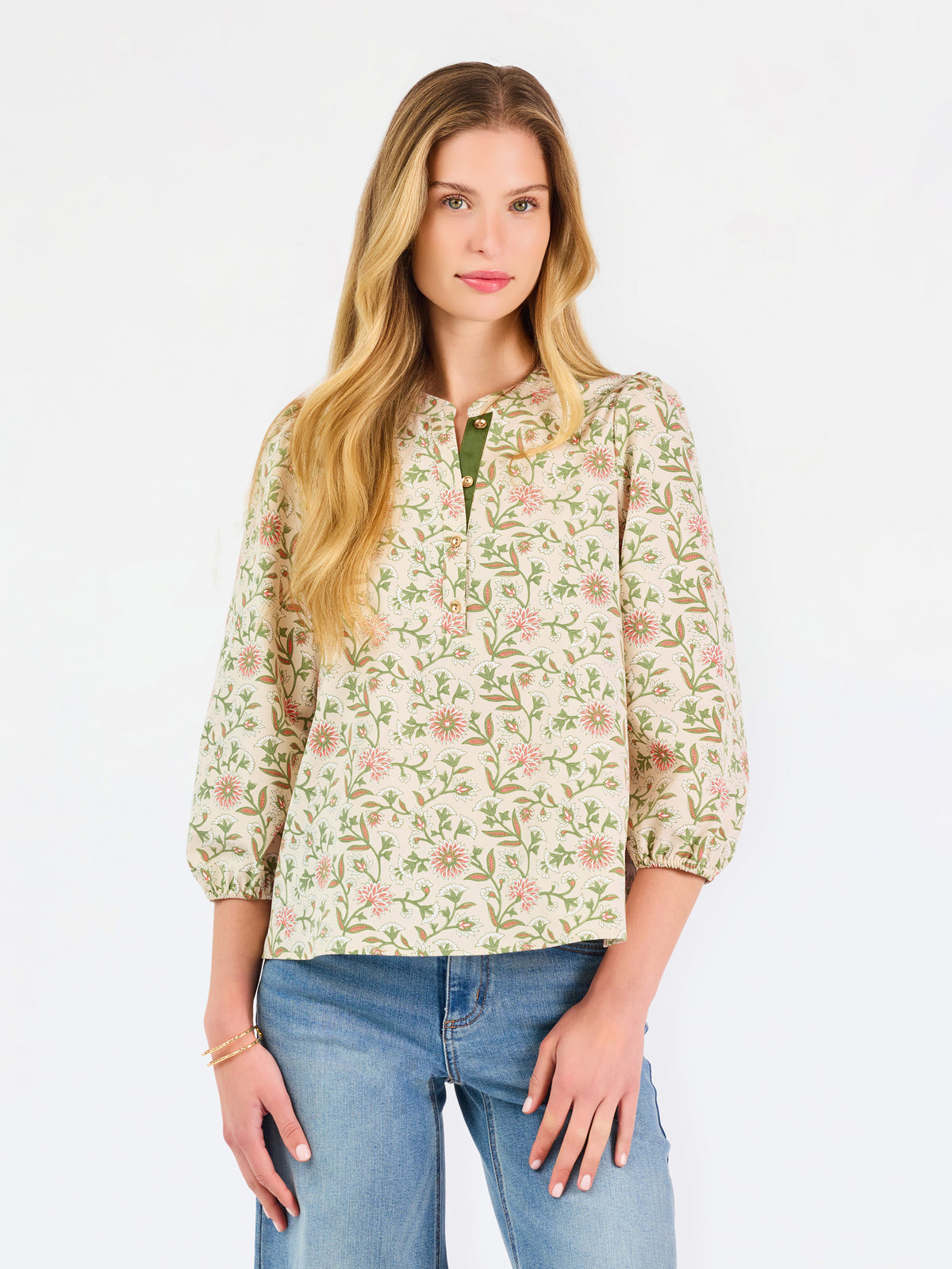 Woman wearing a tan floral blouse and jeans on a white background