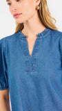 A woman modeling a blue short-sleeve puff-sleeve blouse with a split neckline, paired with cream wide-leg pants and brown flat sandals, against a plain white studio background.