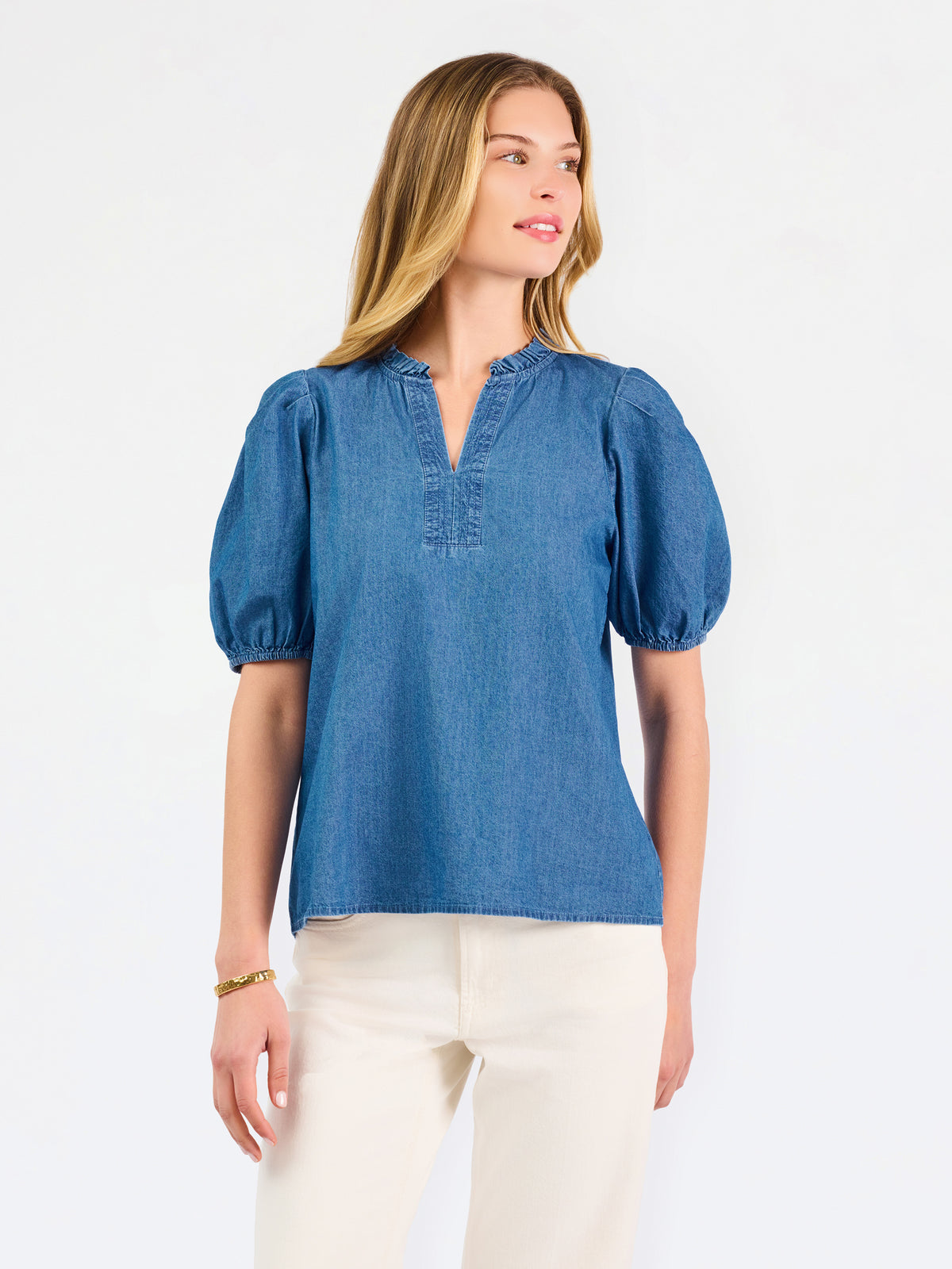 A woman modeling a blue short-sleeve puff-sleeve blouse with a split neckline, paired with cream wide-leg pants and brown flat sandals, against a plain white studio background.