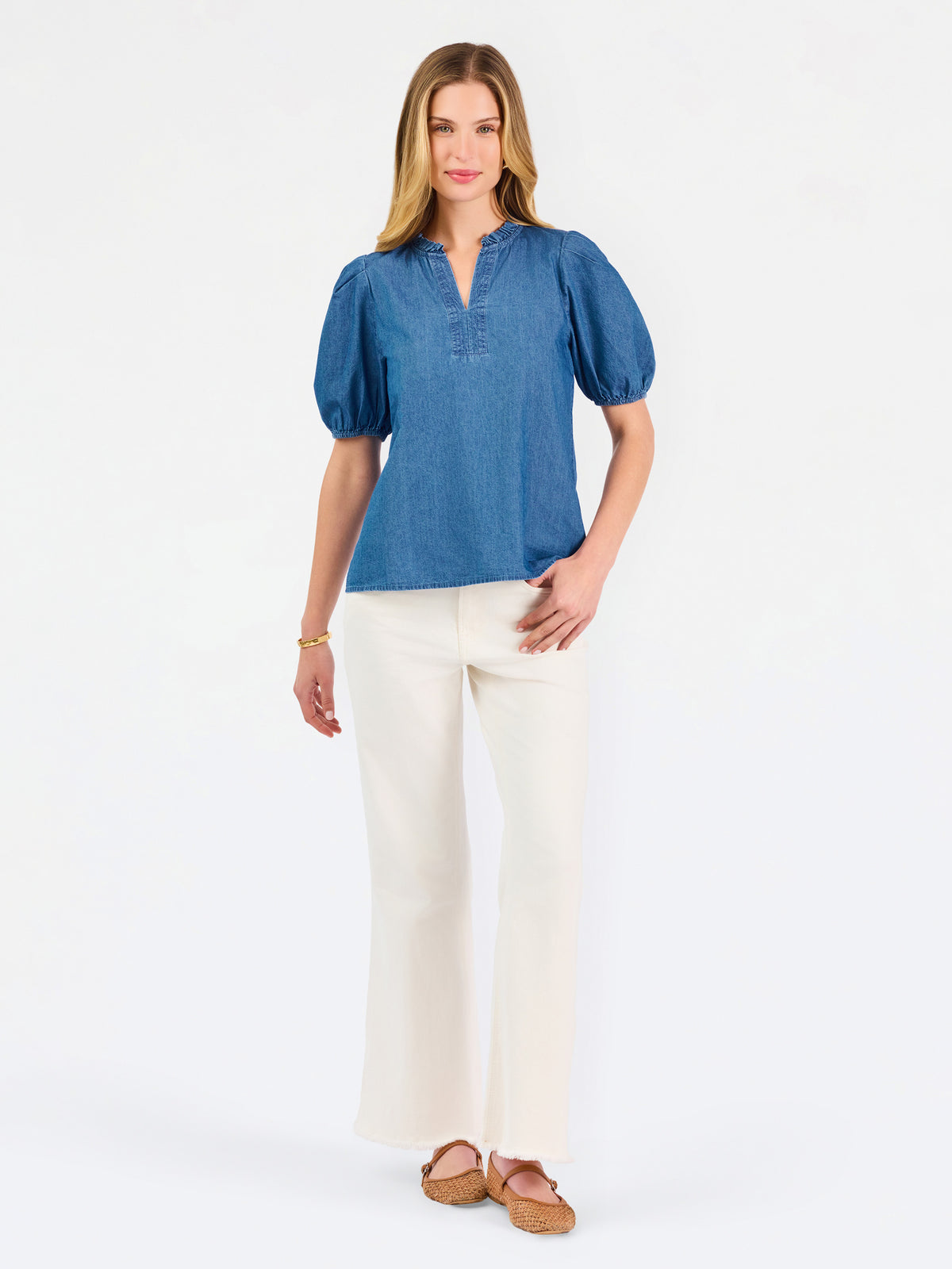 A woman modeling a blue short-sleeve puff-sleeve blouse with a split neckline, paired with cream wide-leg pants and brown flat sandals, against a plain white studio background.