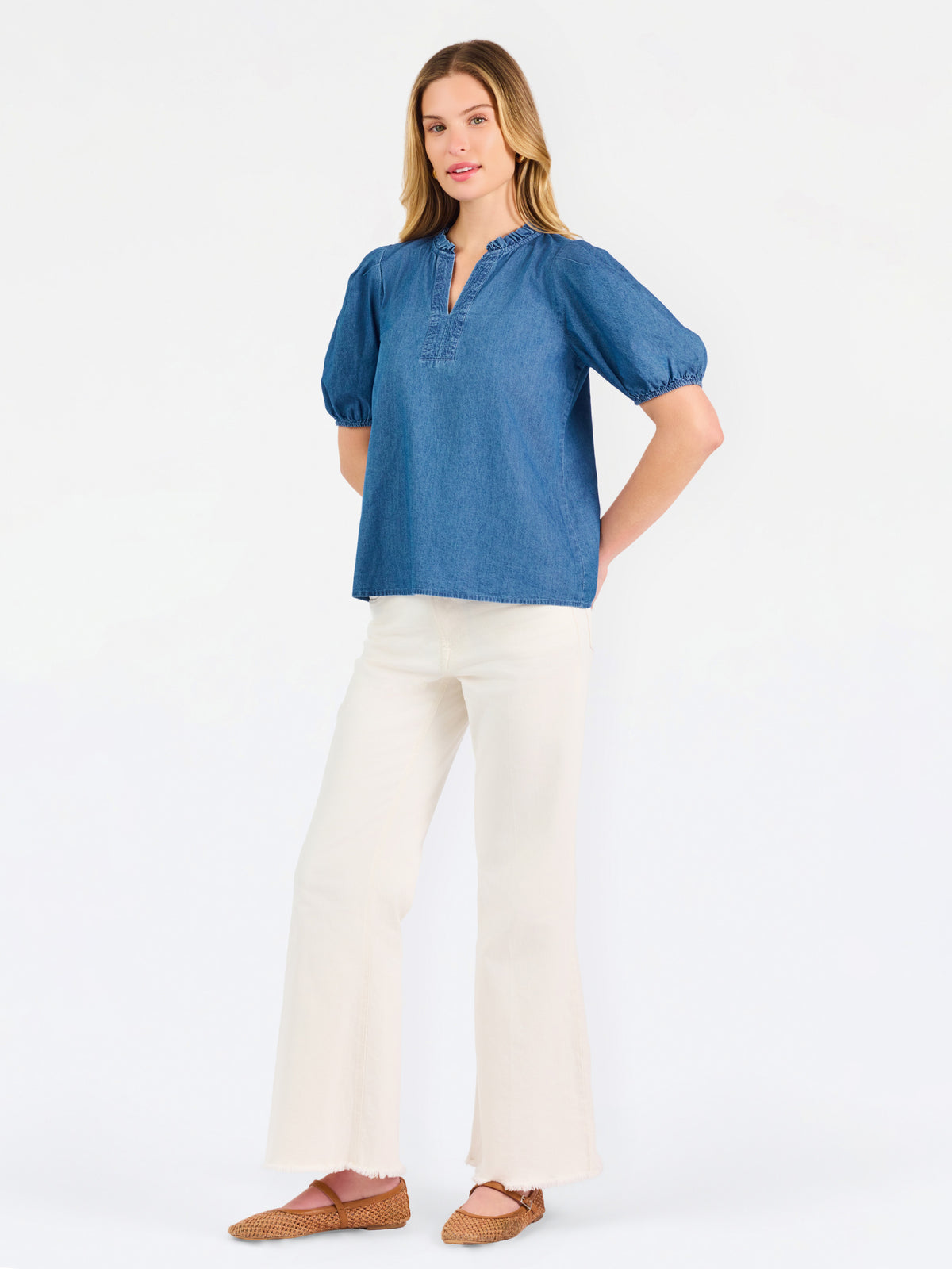 A woman modeling a blue short-sleeve puff-sleeve blouse with a split neckline, paired with cream wide-leg pants and brown flat sandals, against a plain white studio background.