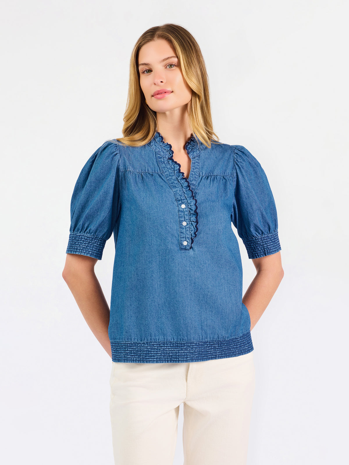 Blonde woman wearing a short sleeve denim colored top with navy scalloped trim