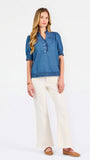 Blonde woman wearing a short sleeve denim colored top with navy scalloped trim
