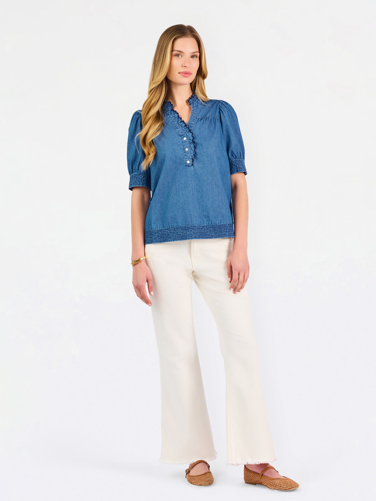 Blonde woman wearing a short sleeve denim colored top with navy scalloped trim