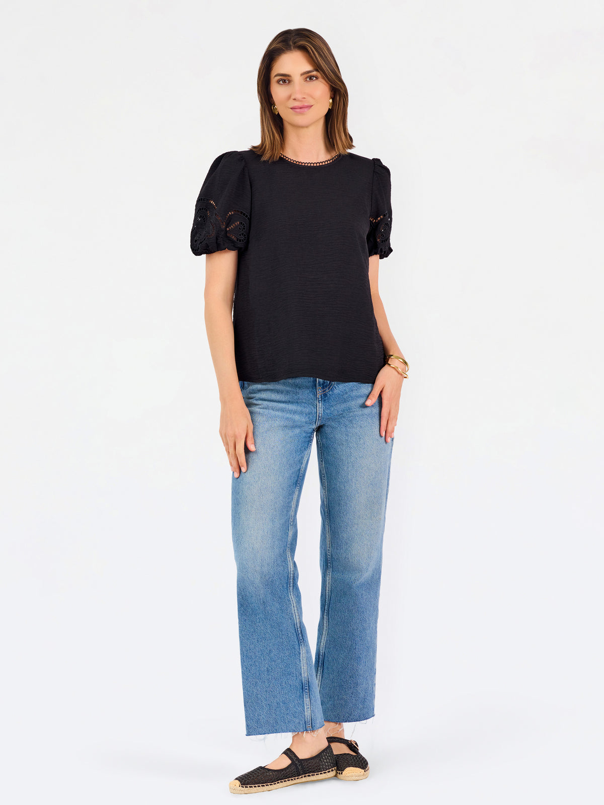 Short haired brunette woman wearing a short sleeve black colored top with cut out detail on puff sleeves