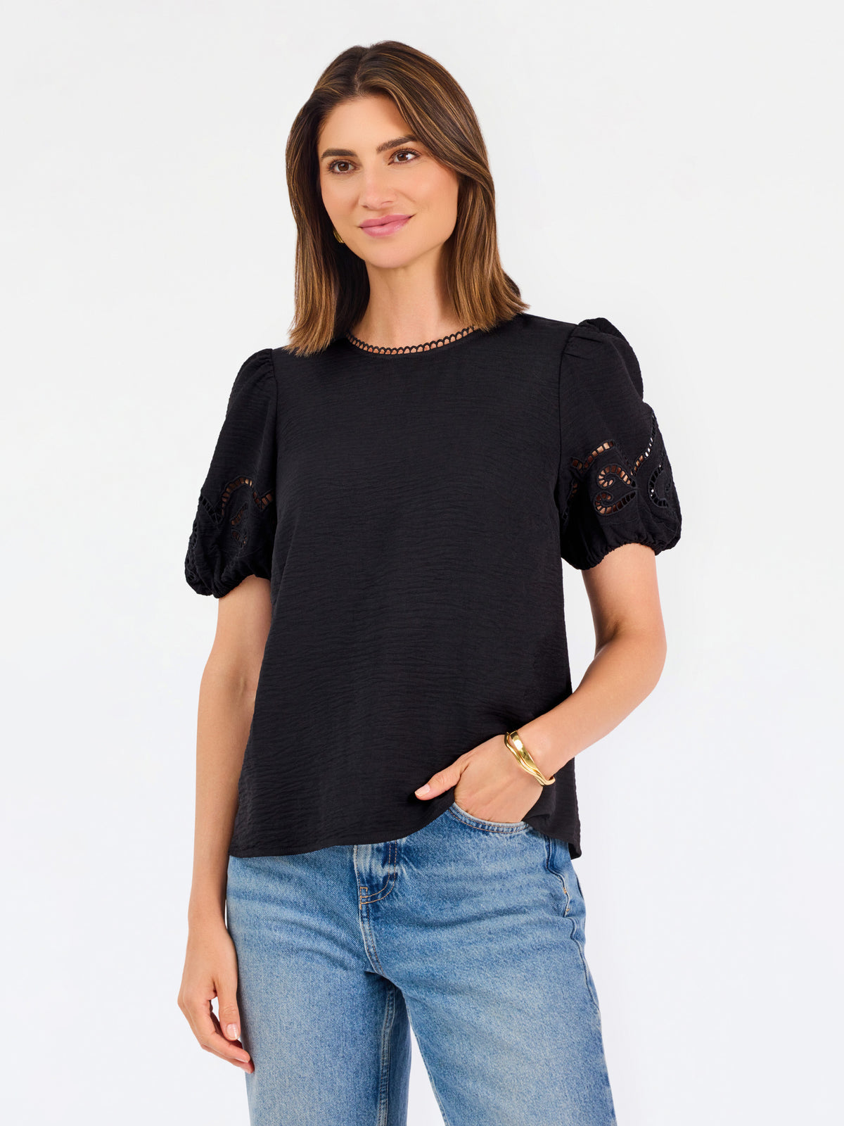 Short haired brunette woman wearing a short sleeve black colored top with cut out detail on puff sleeves