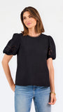 Short haired brunette woman wearing a short sleeve black colored top with cut out detail on puff sleeves