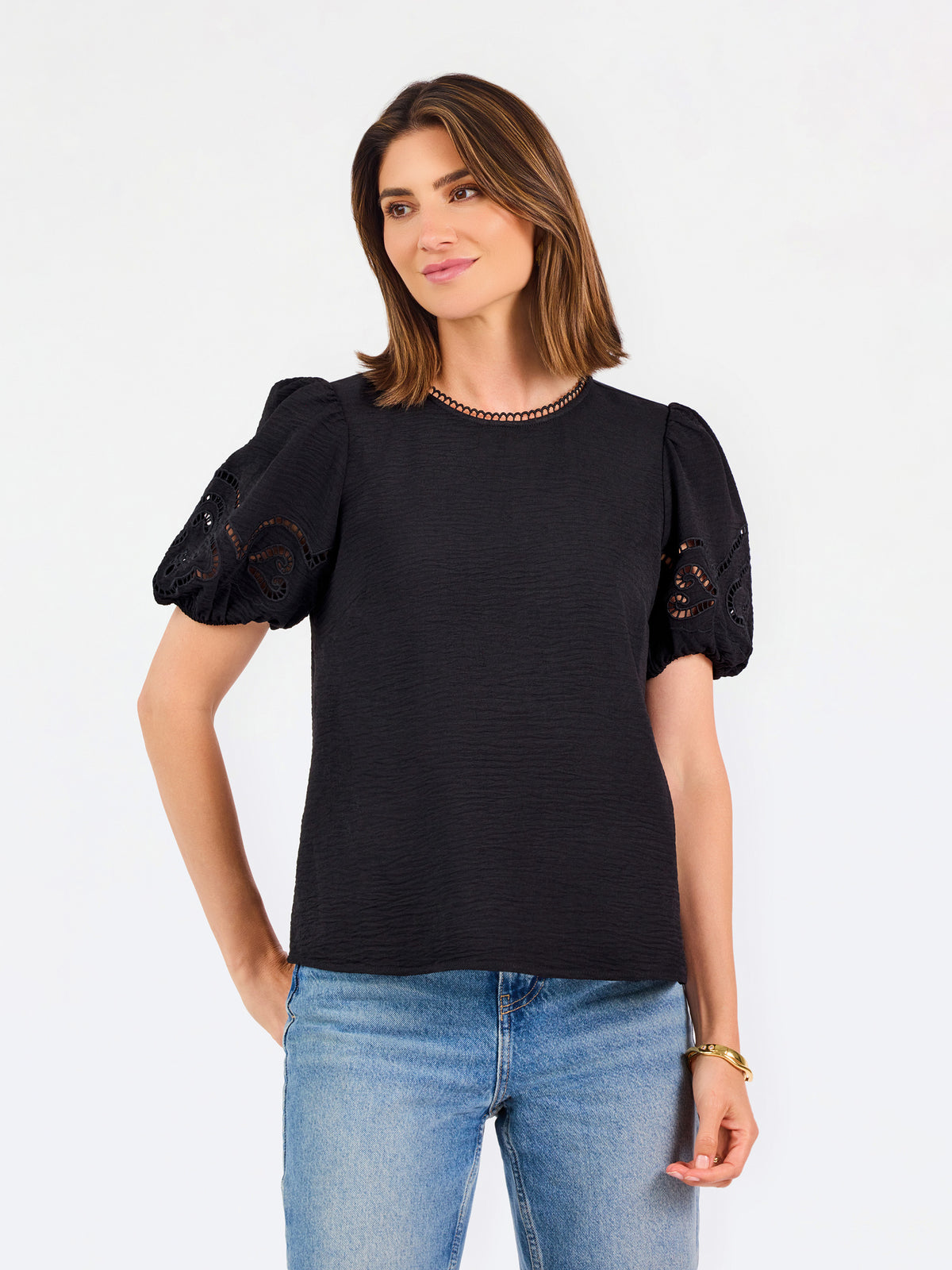 Short haired brunette woman wearing a short sleeve black colored top with cut out detail on puff sleeves