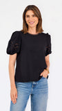 Short haired brunette woman wearing a short sleeve black colored top with cut out detail on puff sleeves