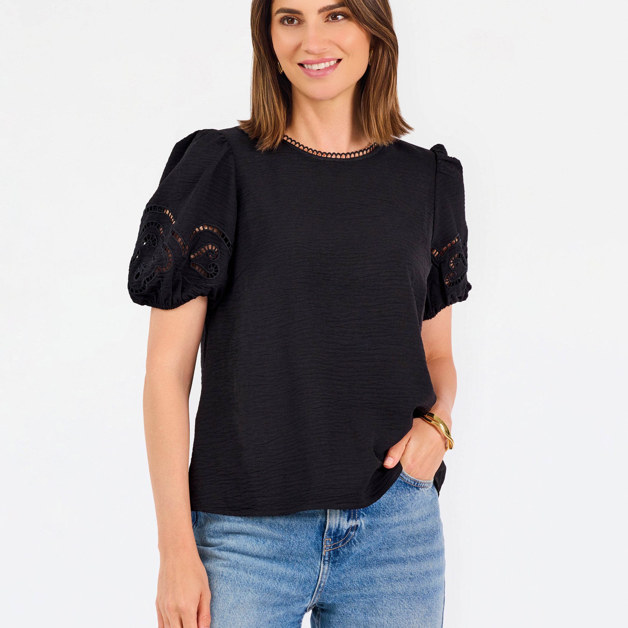 Short haired brunette woman wearing a short sleeve black colored top with cut out detail on puff sleeves