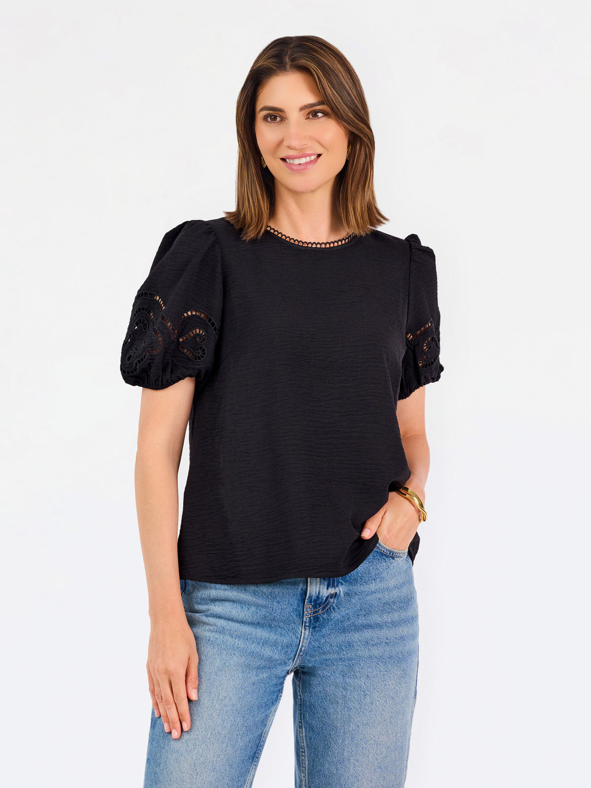 Short haired brunette woman wearing a short sleeve black colored top with cut out detail on puff sleeves