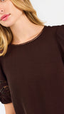 Blonde woman wearing a short sleeve brown colored top with cut out detail on puff sleeves