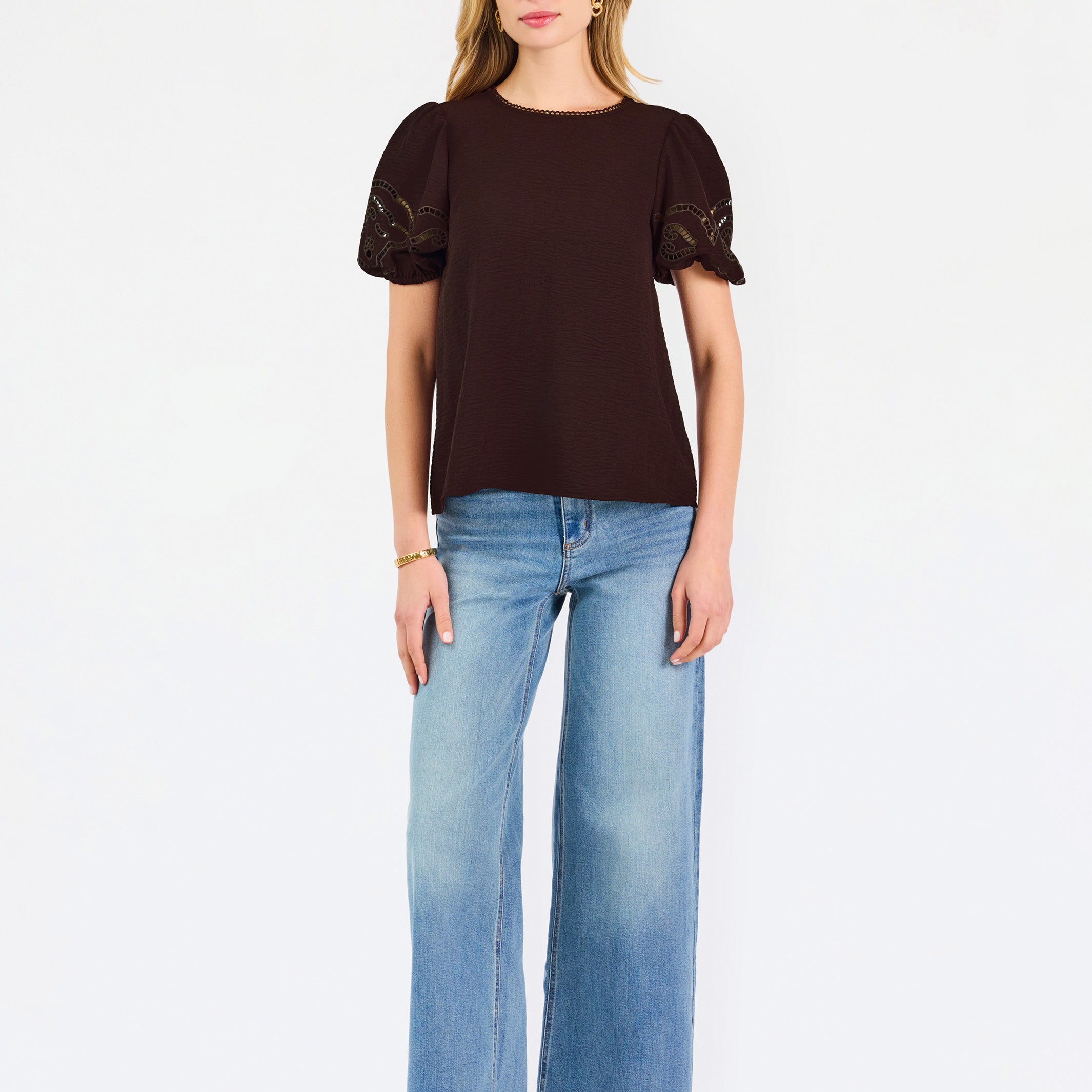 Blonde woman wearing a short sleeve brown colored top with cut out detail on puff sleeves