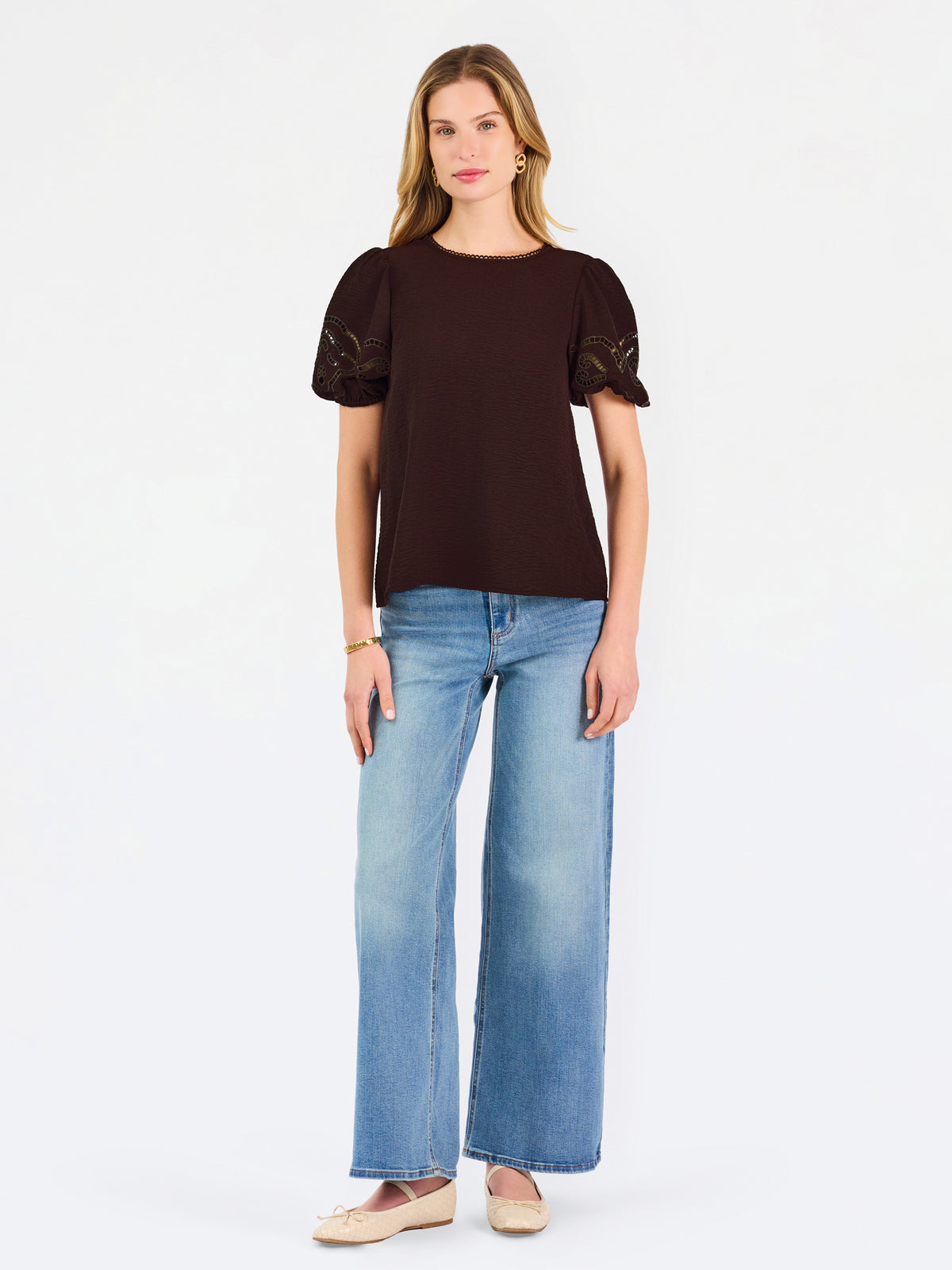 Blonde woman wearing a short sleeve brown colored top with cut out detail on puff sleeves