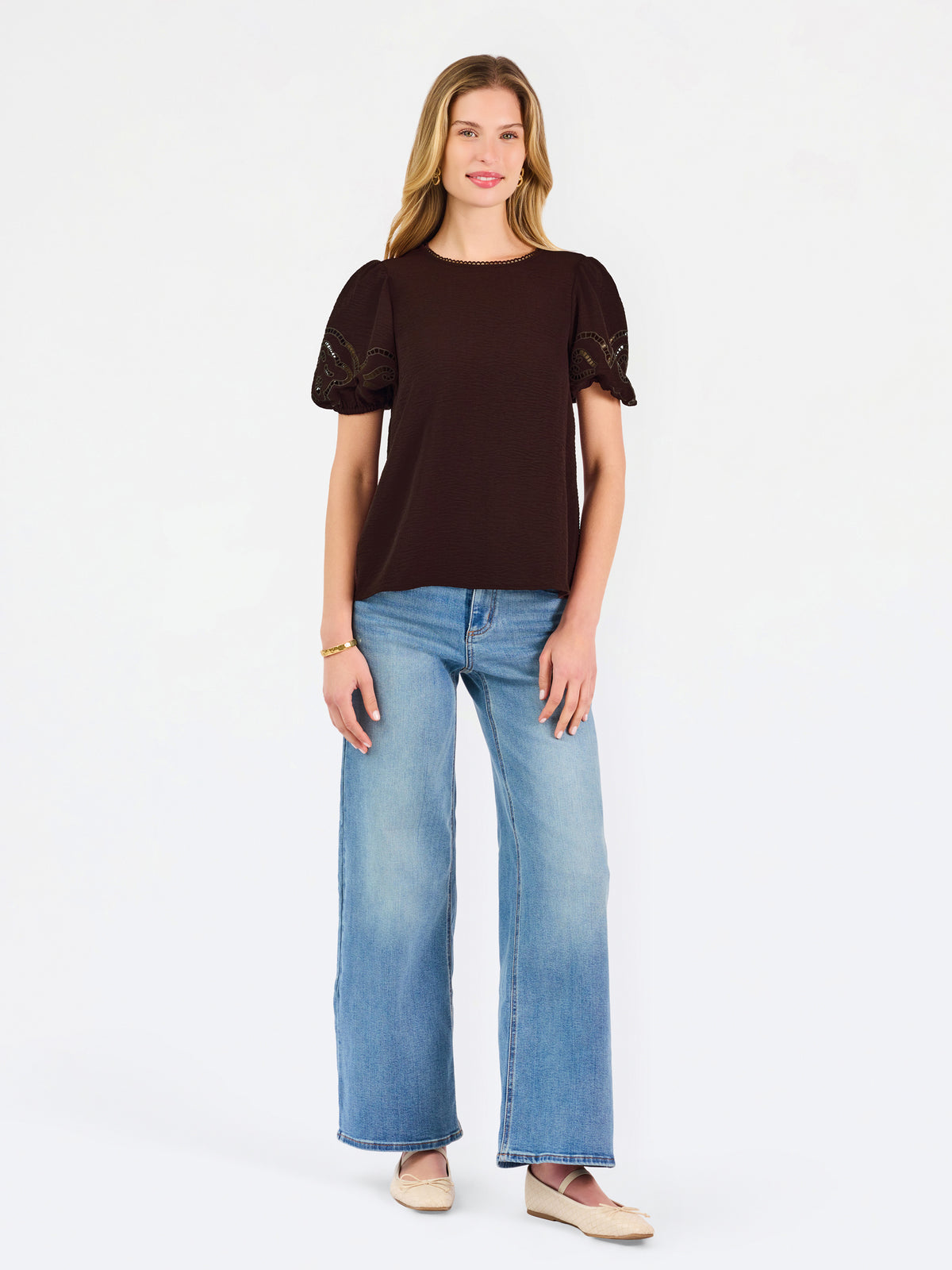 Blonde woman wearing a short sleeve brown colored top with cut out detail on puff sleeves