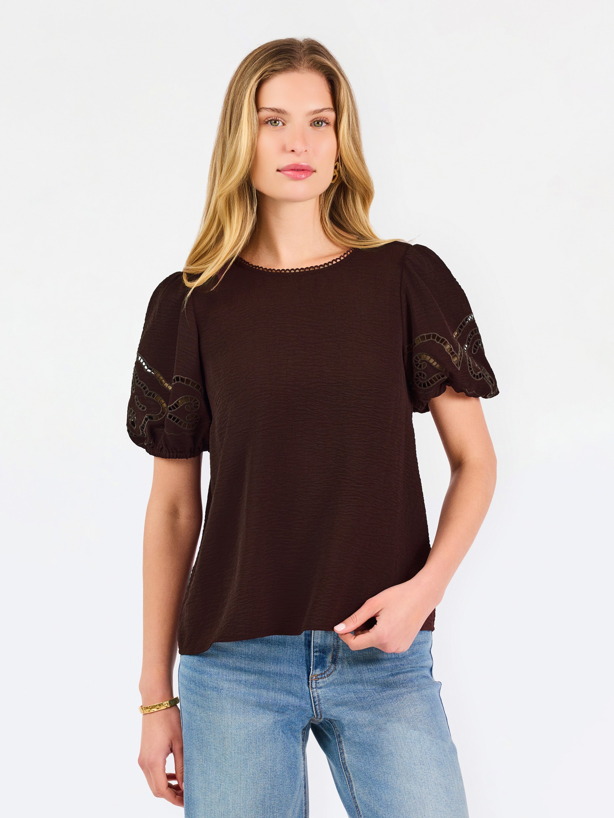 Blonde woman wearing a short sleeve brown colored top with cut out detail on puff sleeves