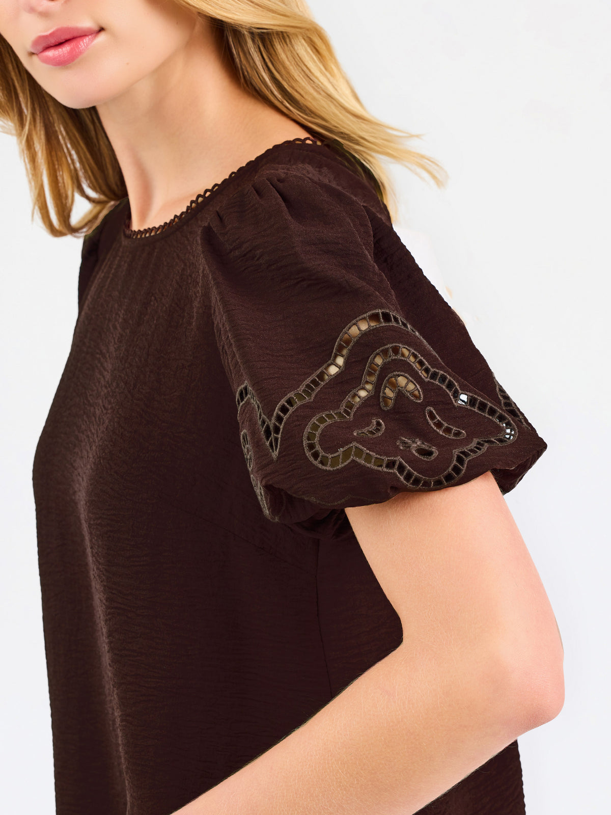 Blonde woman wearing a short sleeve brown colored top with cut out detail on puff sleeves