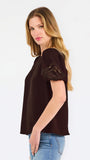 Blonde woman wearing a short sleeve brown colored top with cut out detail on puff sleeves